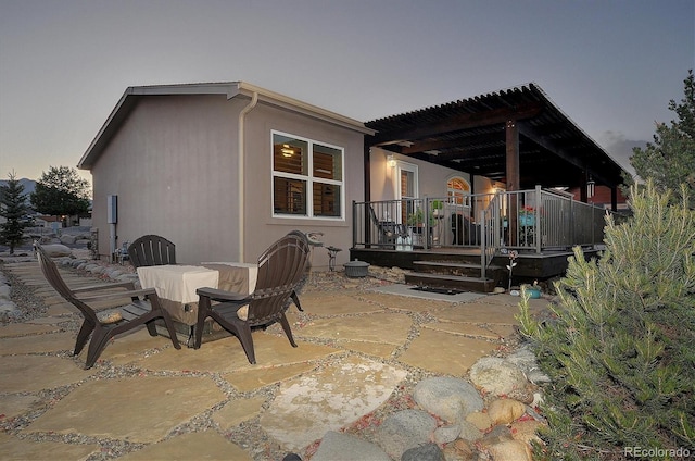 back house at dusk featuring a patio area