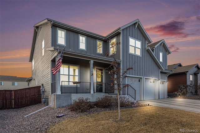 view of front of house featuring covered porch, concrete driveway, board and batten siding, fence, and a garage