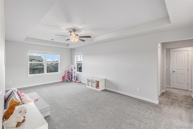 playroom featuring carpet floors, a tray ceiling, a ceiling fan, and baseboards