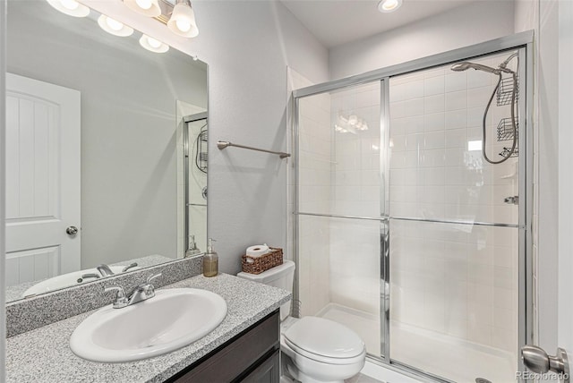 full bathroom featuring a shower stall, toilet, and vanity