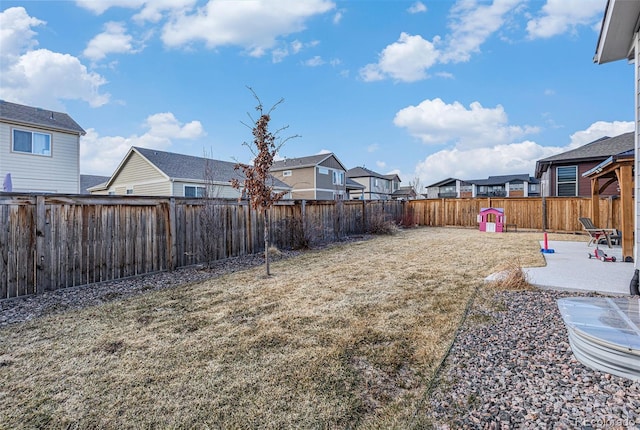 view of yard featuring a patio area, a fenced backyard, and a residential view