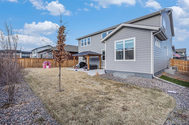 back of property with a fenced backyard and a gazebo