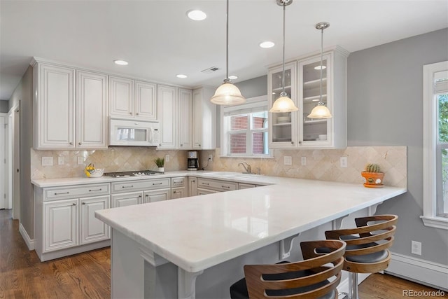 3330 E Tennessee Ave, Denver, CO 80209 - kitchen featuring white microwave, a kitchen bar, wood finished floors, a peninsula, and recessed lighting