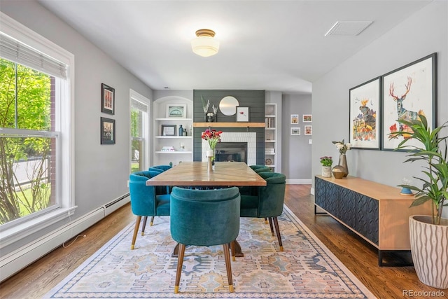 3330 E Tennessee Ave, Denver, CO 80209 - dining area featuring baseboard heating, a glass covered fireplace, built in shelves, and wood finished floors