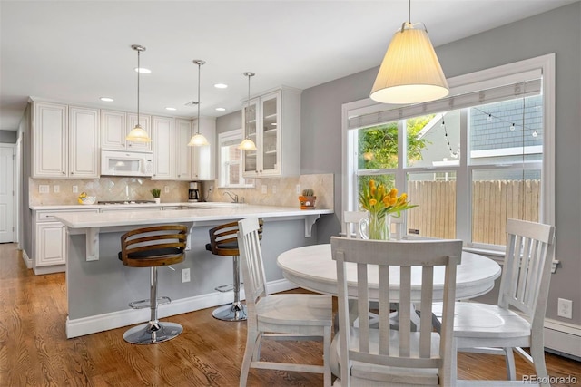 3330 E Tennessee Ave, Denver, CO 80209 - kitchen with white microwave, light countertops, glass insert cabinets, gas stovetop, and decorative backsplash