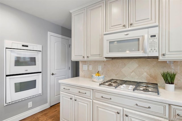 3330 E Tennessee Ave, Denver, CO 80209 - kitchen featuring white appliances, tasteful backsplash, light countertops, and light wood-style floors