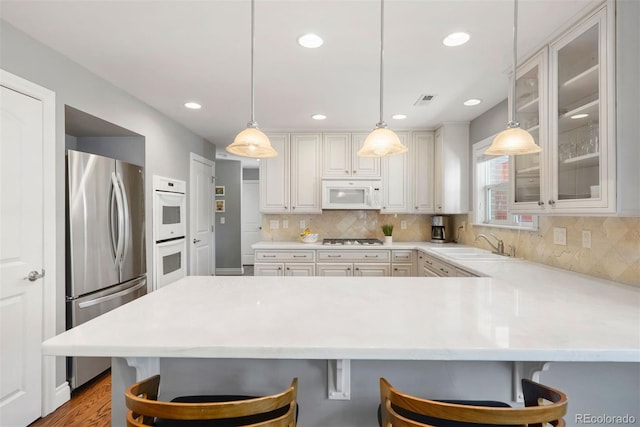 3330 E Tennessee Ave, Denver, CO 80209 - kitchen with white appliances, a peninsula, a sink, a kitchen bar, and glass insert cabinets