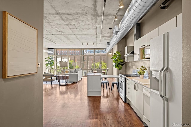 1499 Blake St Unit 2C, Denver, CO 80202 - kitchen with white appliances, rail lighting, dark wood-style floors, white cabinetry, and light countertops