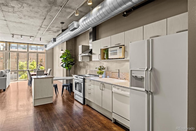 1499 Blake St Unit 2C, Denver, CO 80202 - kitchen with white appliances, rail lighting, wall chimney range hood, dark wood finished floors, and hanging light fixtures