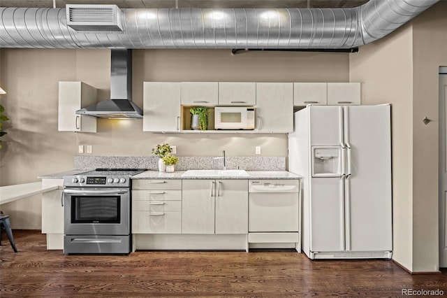 1499 Blake St Unit 2C, Denver, CO 80202 - kitchen with white appliances, wall chimney range hood, dark wood finished floors, and light stone counters