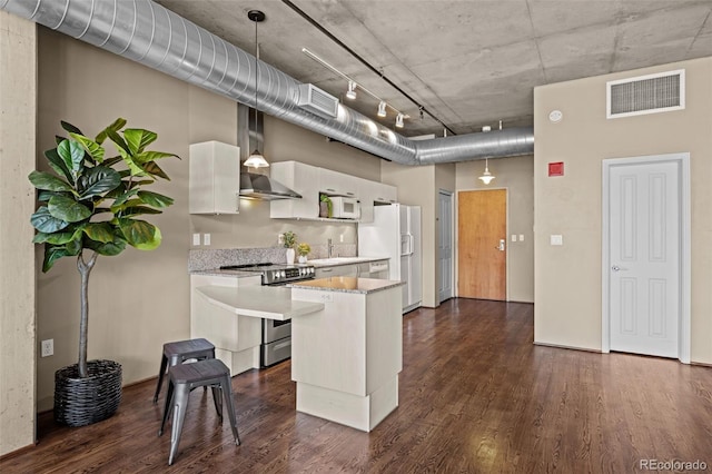 1499 Blake St Unit 2C, Denver, CO 80202 - kitchen with white appliances, light countertops, wall chimney exhaust hood, dark wood-type flooring, and white cabinets
