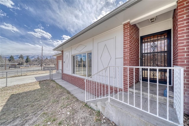 view of side of home featuring brick siding and fence