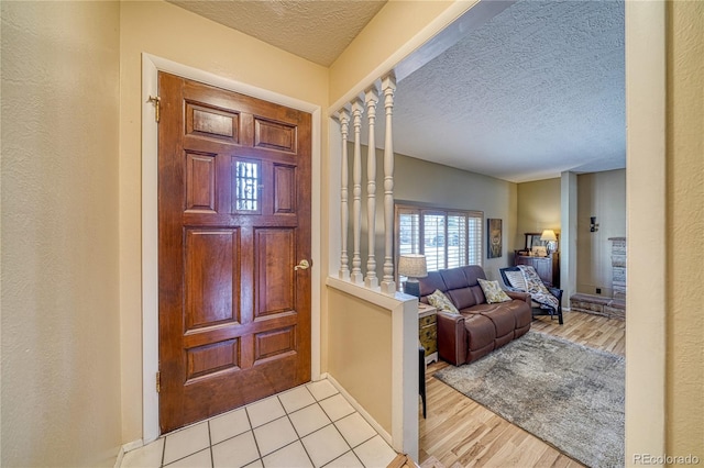 foyer with a textured ceiling, a textured wall, and wood finished floors