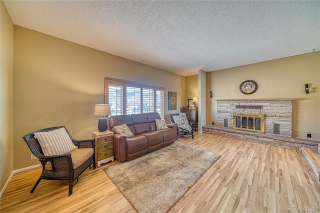 living area with baseboards, a textured ceiling, wood finished floors, and a fireplace