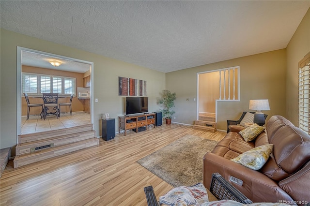 living room featuring a textured ceiling, baseboards, and wood finished floors