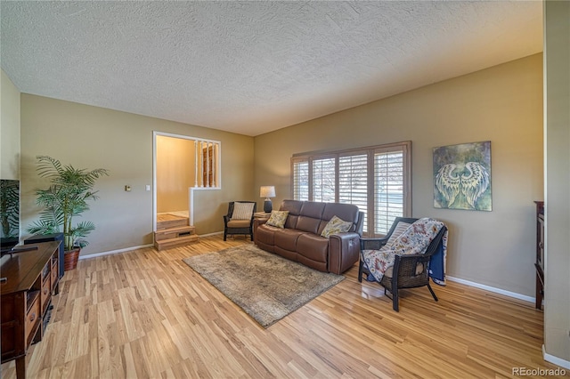 living room featuring light wood-style flooring, baseboards, and a textured ceiling