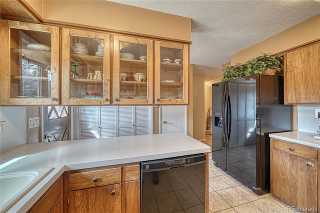 kitchen with black appliances, light countertops, brown cabinets, a textured ceiling, and a sink