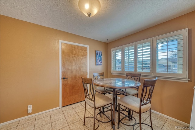 dining space featuring light tile patterned floors, baseboards, and a textured ceiling