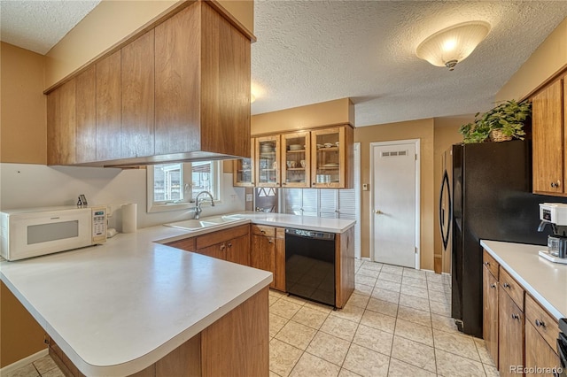 kitchen featuring black appliances, a sink, a peninsula, light countertops, and glass insert cabinets