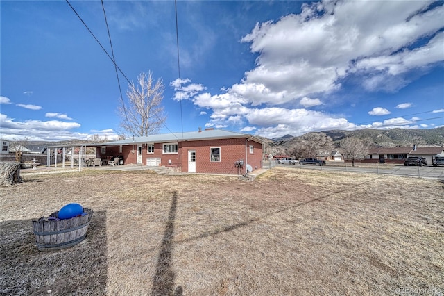 rear view of property with a mountain view, brick siding, and fence