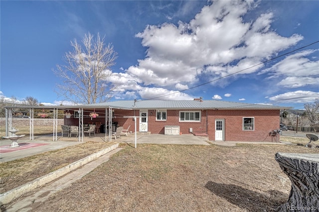 rear view of property featuring a patio, brick siding, and metal roof