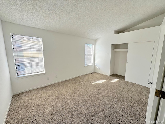 unfurnished bedroom featuring a textured ceiling, carpet floors, vaulted ceiling, and a closet