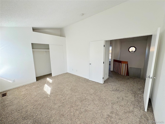 unfurnished bedroom featuring a textured ceiling, lofted ceiling, carpet floors, and a closet