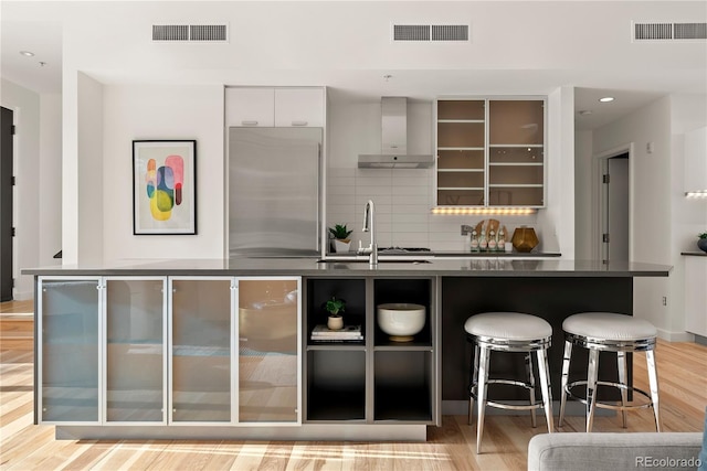 kitchen featuring visible vents, stainless steel refrigerator, and wall chimney range hood