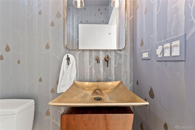 bathroom with vanity, toilet, and wallpapered walls