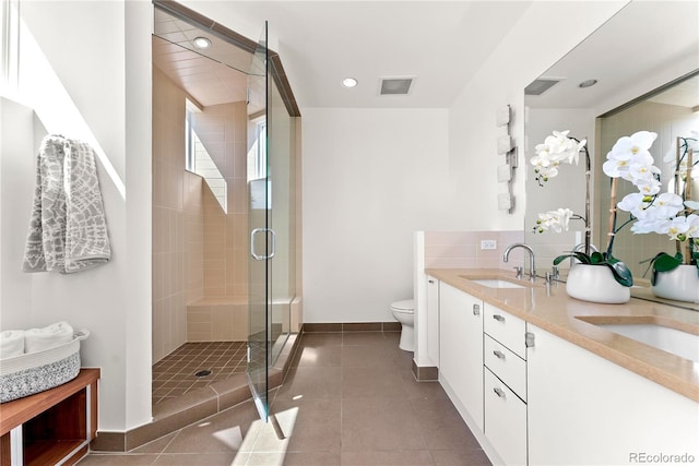 bathroom featuring toilet, a sink, a shower stall, tile patterned flooring, and double vanity