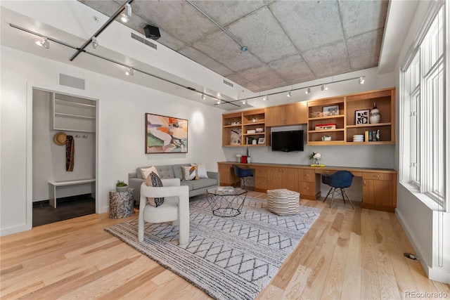 living room with light wood-type flooring, visible vents, track lighting, and built in study area