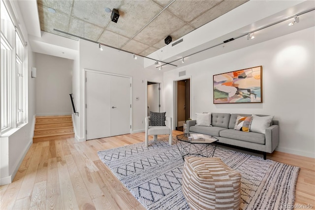 living room with track lighting, light wood-type flooring, and visible vents