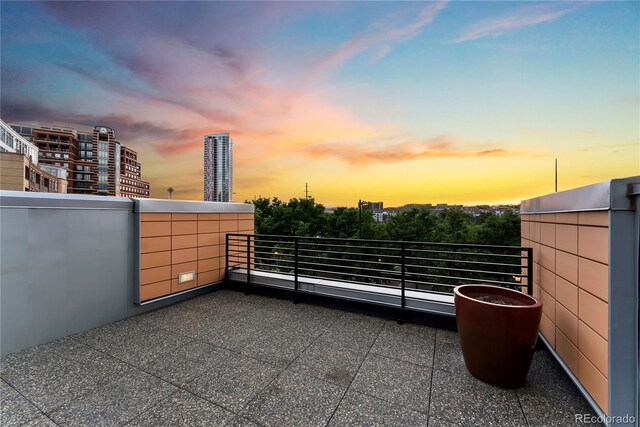 patio terrace at dusk with a balcony and a city view