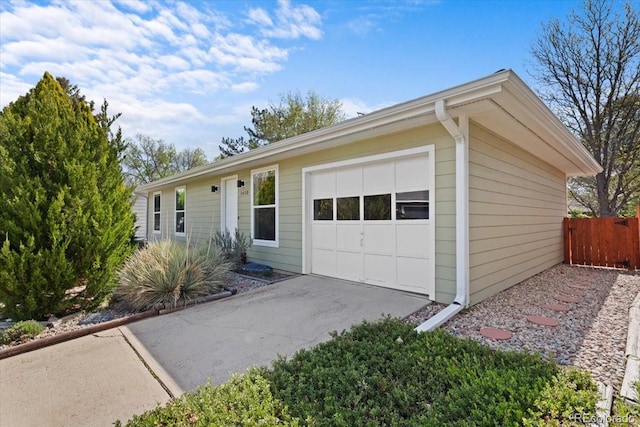 ranch-style house featuring a garage, fence, and driveway