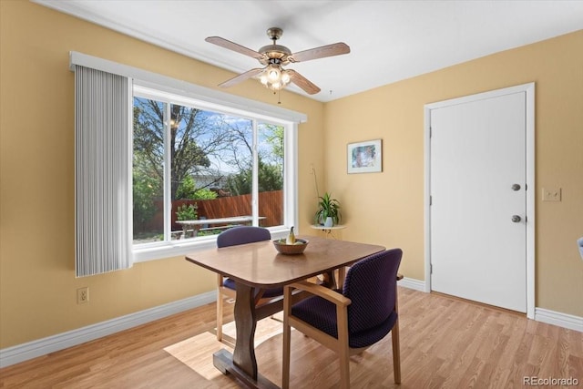 dining room featuring baseboards, light wood finished floors, and a ceiling fan