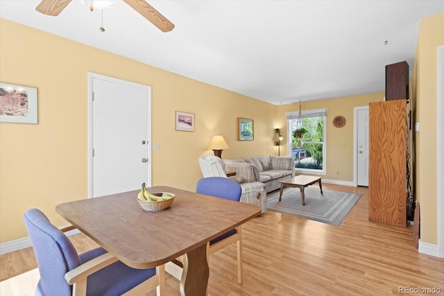 dining area with light wood finished floors, ceiling fan, and baseboards
