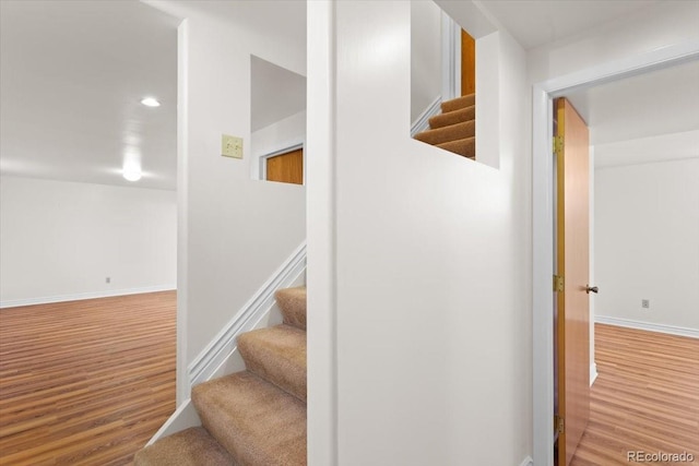 staircase featuring wood finished floors, baseboards, and recessed lighting