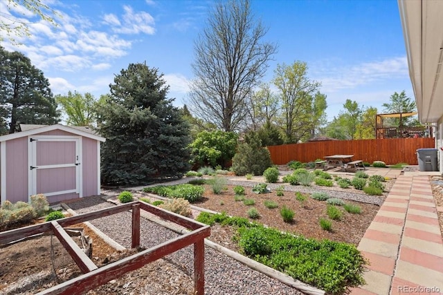 view of yard featuring a garden, a storage shed, fence, an outdoor structure, and a patio area