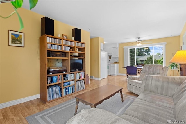 living room featuring a ceiling fan, light wood-type flooring, and baseboards