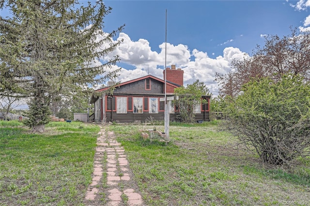 back of house featuring a chimney and a lawn
