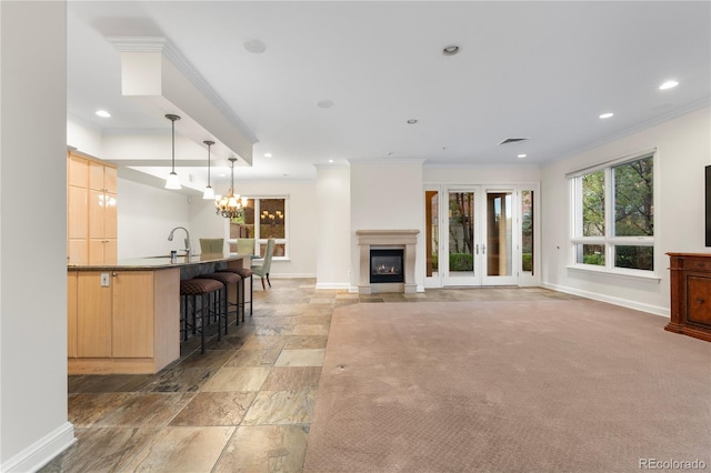 carpeted living room with sink, crown molding, french doors, and an inviting chandelier