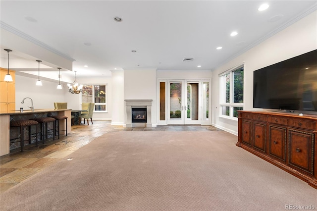 living room with light carpet, a chandelier, ornamental molding, french doors, and sink