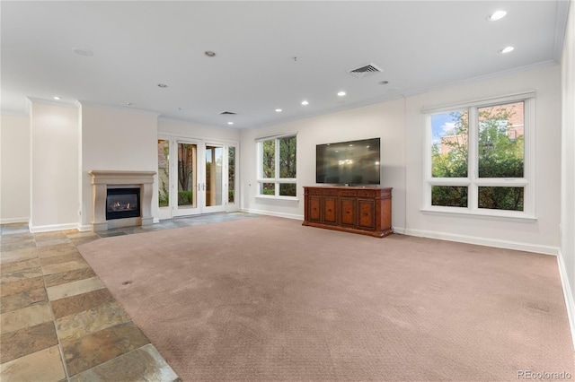 unfurnished living room featuring crown molding, a wealth of natural light, and light colored carpet