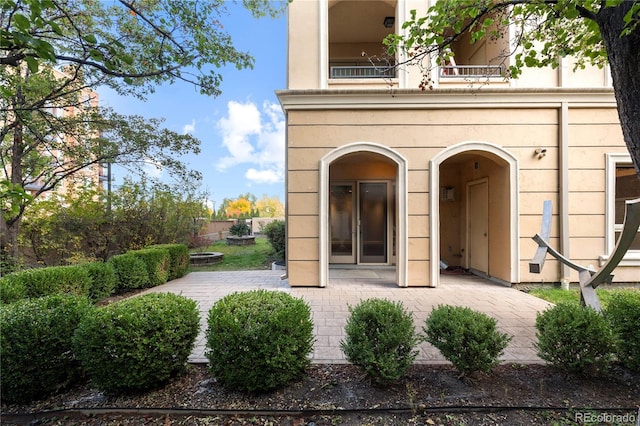 view of exterior entry with a patio and a balcony