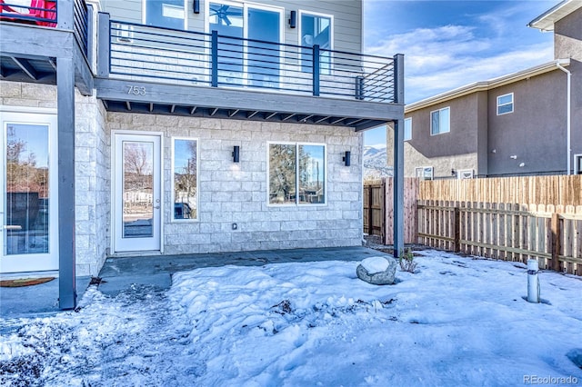 snow covered property entrance featuring a balcony