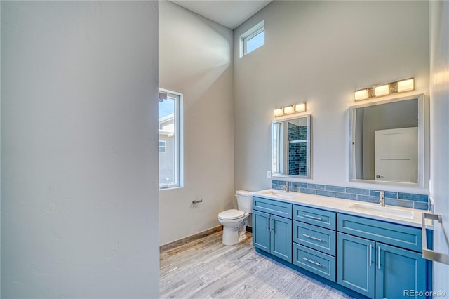 bathroom with hardwood / wood-style floors, a towering ceiling, toilet, decorative backsplash, and vanity