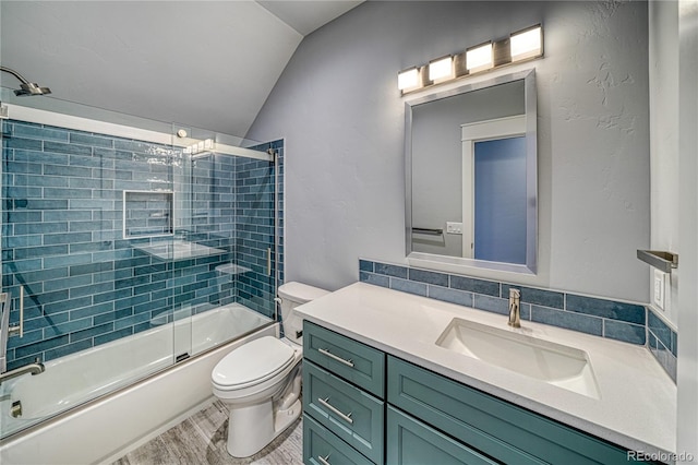 full bathroom featuring bath / shower combo with glass door, vaulted ceiling, toilet, vanity, and hardwood / wood-style flooring