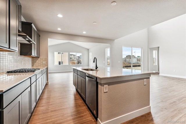 kitchen with appliances with stainless steel finishes, light wood-type flooring, sink, a center island with sink, and lofted ceiling