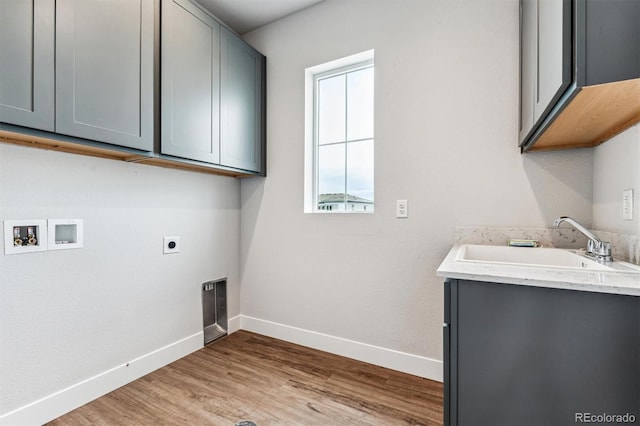 clothes washing area featuring cabinets, sink, washer hookup, hookup for an electric dryer, and light hardwood / wood-style floors