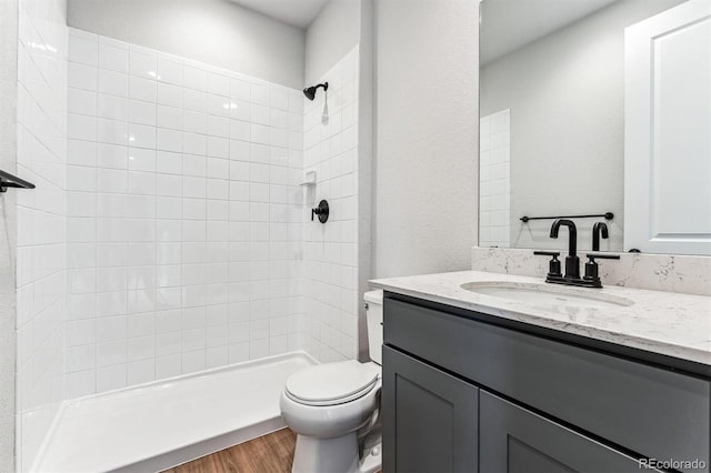 bathroom with vanity, toilet, wood-type flooring, and tiled shower